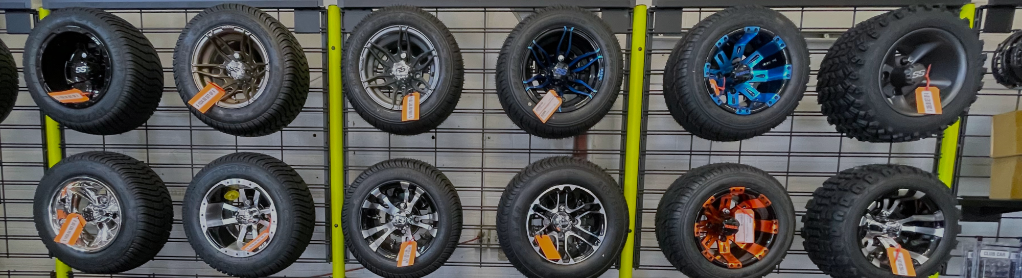 Golf cart wheel and tire sets displayed on a wall.